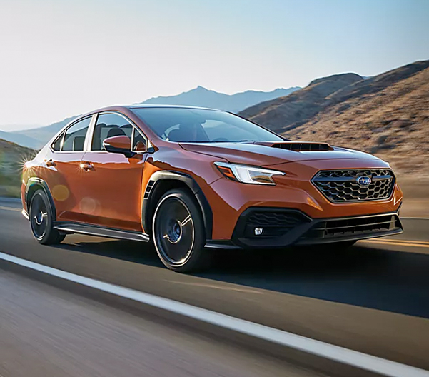 3/4 View of an Orange Subaru Driving down the road