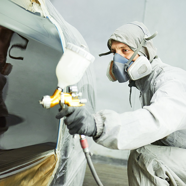 Collision repair tech painting a vehicle