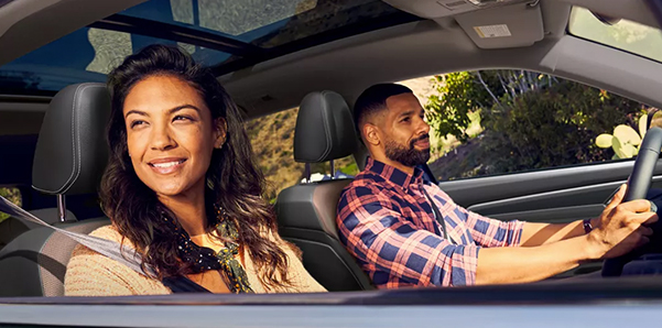 The passenger window of an Atlas in Racing Green Metallic reveals a couple driving and a sunroof.