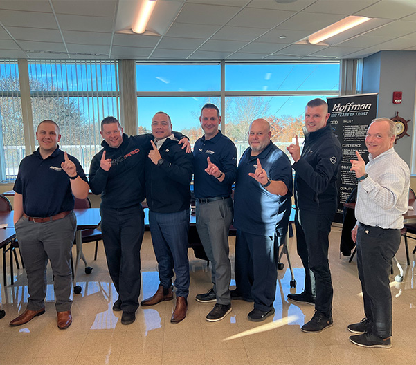 Hoffman Leadership team standing in front of a table posing for a picture