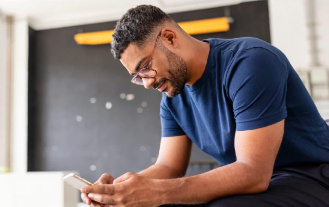 A man in a blue shirt looking at a cell phone.