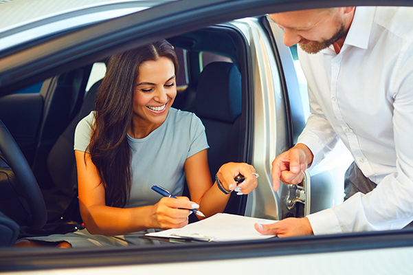 A young woman buys a car in a car showroom.