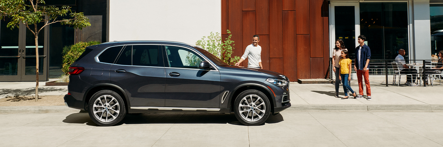 Happy family walking by their new BMW